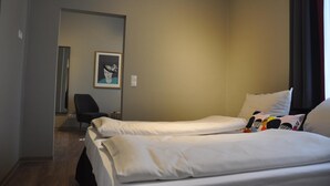 Una habitación de hotel con dos camas, una silla y un cuadro en la pared.