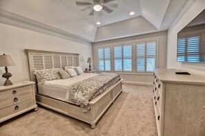Ein Schlafzimmer mit Bett, Nachttisch, Kommode und Deckenventilator.