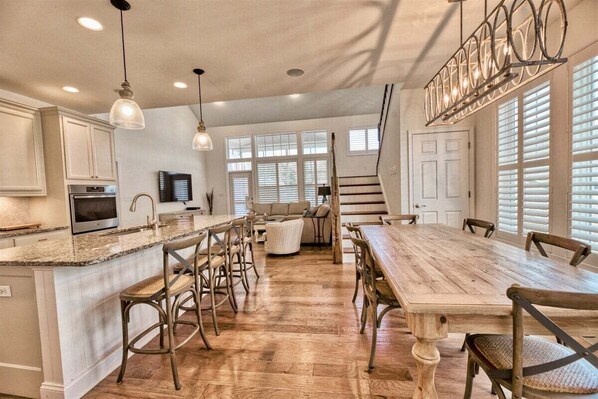 A spacious kitchen with a wooden dining table, bar stools, and a large island.