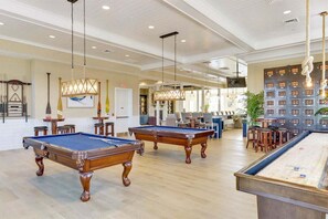 A pool table area with multiple pool tables, a bar area, and a seating area with chairs and tables.