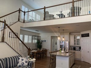 A spacious interior with a dining area, kitchen, and a staircase leading to an upper level.