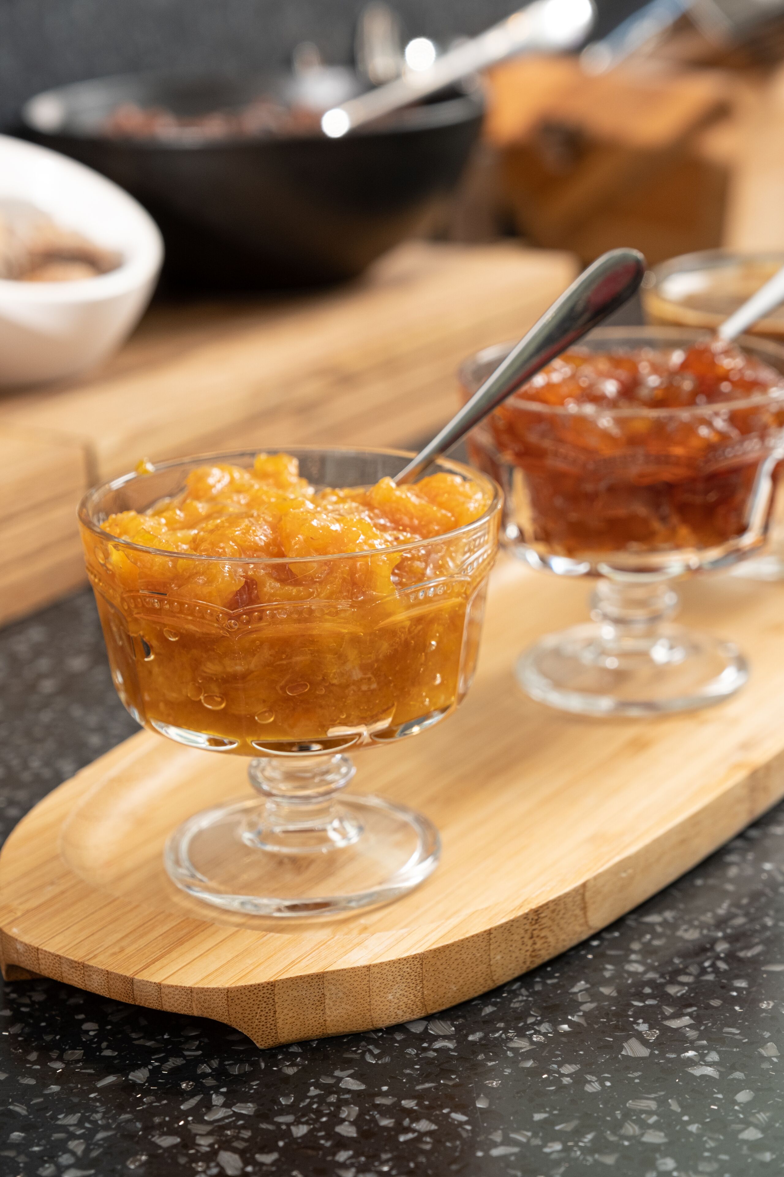 Two glass bowls of fruit compote on a wooden board.