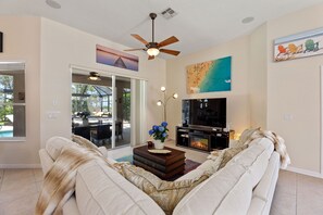 A living room with a sofa, a coffee table with books, a fireplace, and a television. - Stunning Sunset villa,Spectacular saltwater pool & spa. 3 bed,2 bath (Davenport)