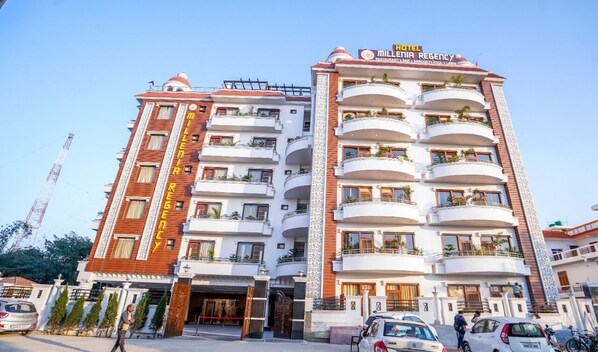 Um hotel de vários andares com varandas, uma entrada central e uma placa indicando que é um hotel e restaurante.