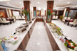 Disposição de buffet com várias estações de comida e áreas de estar.
