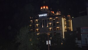 Un edificio de varios pisos con letreros iluminados y una estructura en forma de cúpula en la parte superior.