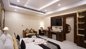 Una habitación de hotel con cama, escritorio, silla, televisor y armario.