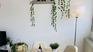 A dining area with a round table, white chairs, and a floor lamp. - Charming Duplex Trouville / Deauville 5mn Train Station (Trouville-sur-Mer)