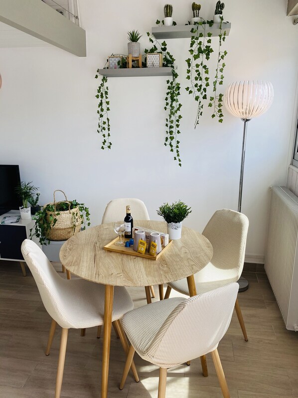 A dining area with a round table, white chairs, and a floor lamp.