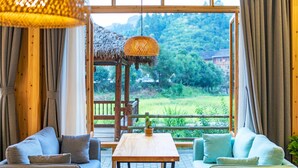 Una habitación con una mesa de madera, dos sofás y un ventanal con vistas a un paisaje verde.