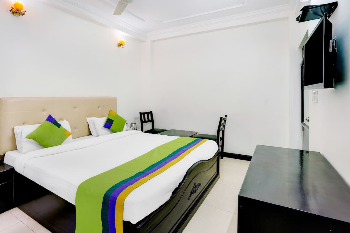 A hotel room with a bed, a small table, a chair, and a TV.
