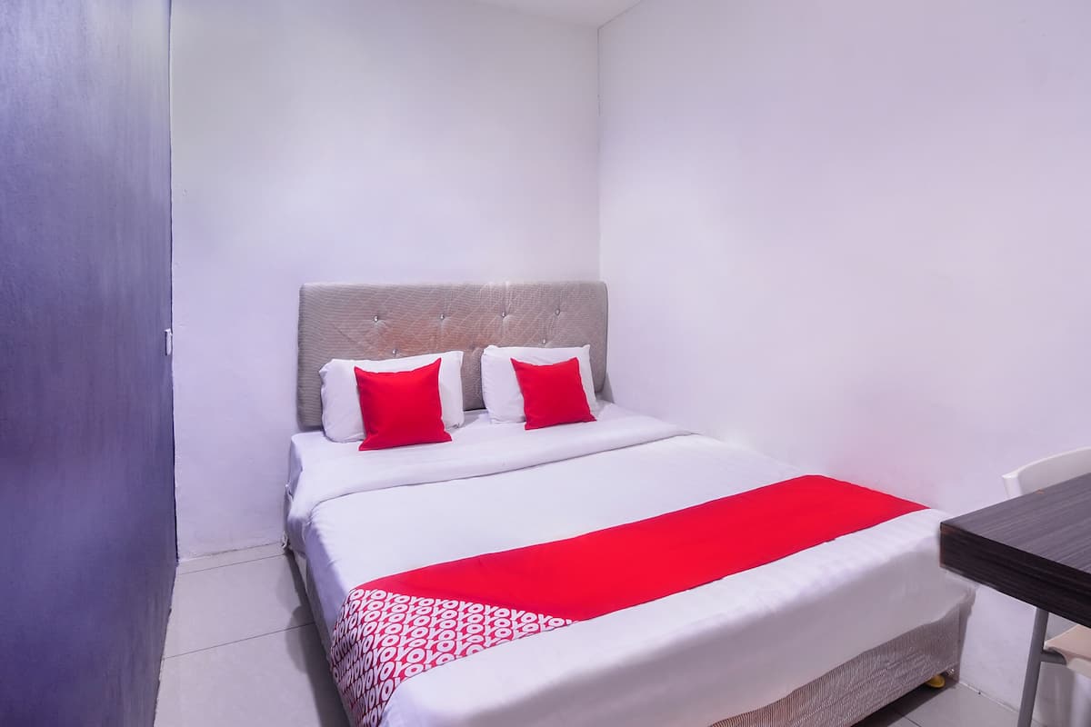 A neatly made bed with white and red bedding, a grey headboard, and a red accent on the bedspread.