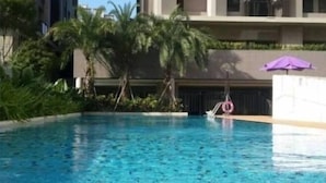 Ein Schwimmbecken mit klarem, blauem Wasser, umgeben von Grünflächen und einem modernen Gebäude im Hintergrund.