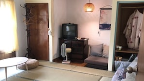 A tatami mat room with a television, a fan, and a wooden wardrobe. - No. 79 Backpacker (Kaohsiung)
