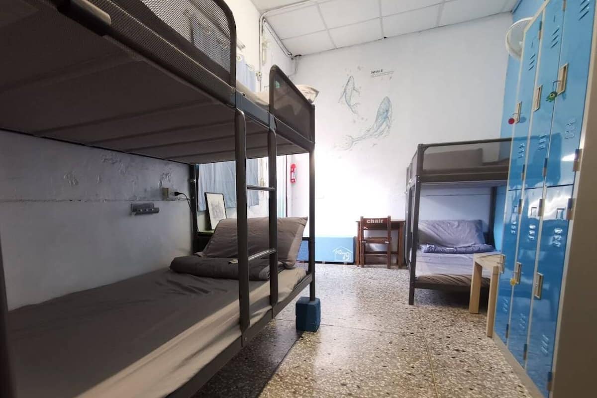 Um quarto de dormitório com beliches, uma cadeira e uma escrivaninha.