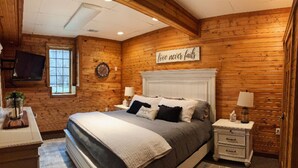 Een gezellige slaapkamer met een groot bed, houten wanden, een wandgemonteerde televisie en een motiverende tekst.