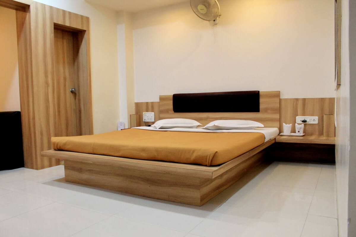 Une chambre moderne avec un lit en bois, des tables de chevet et un téléviseur encastré.