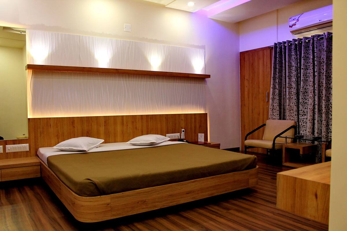 Une chambre d’hôtel moderne avec un lit en bois, une table de chevet, une chaise et un bureau.