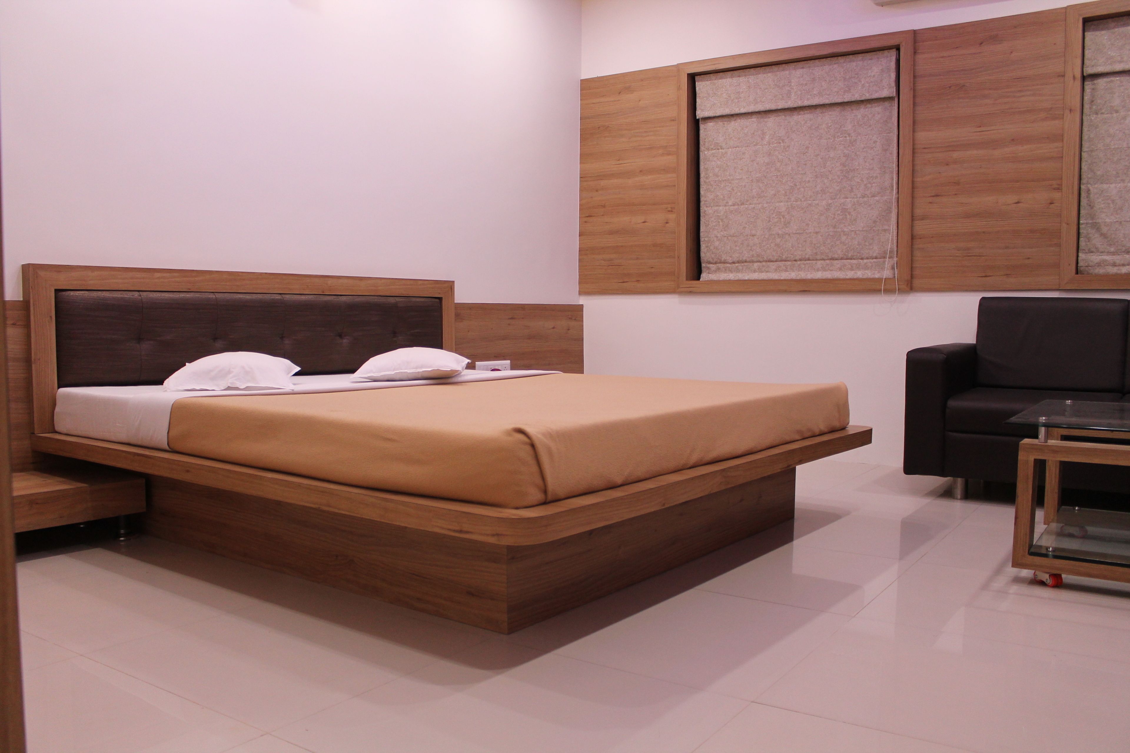 A modern bedroom with a wooden bed, a black sofa, and a glass coffee table.