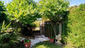 A garden with a wooden fence, potted plants, and a stone birdbath.