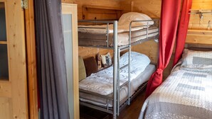 A bunk bed room with wooden walls, a door, and curtains.