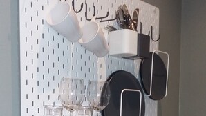 A kitchen with a pegboard wall organizer holding pots, pans, and utensils. - Gästehaus Sonne (Triefenstein)