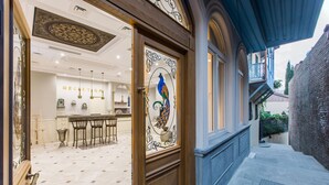Ein Empfangsbereich mit Bar, Stühlen und einer dekorativen Glasdoor mit Vogelmotiv.