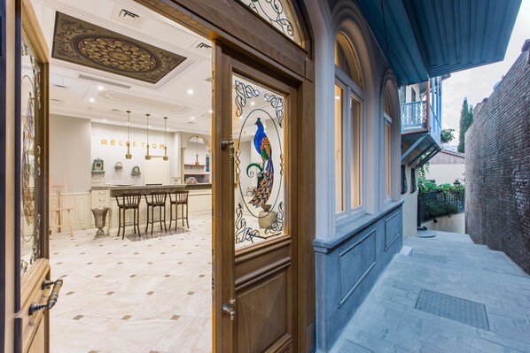 Un área de recepción con bar, sillas y una puerta de cristal decorativa con un diseño de pájaro.