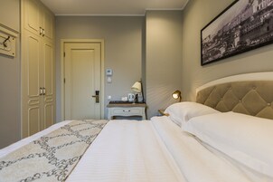 A hotel room with a bed, bedside table, lamp, and a framed picture on the wall.