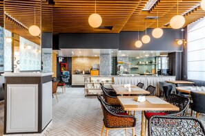 Un interior de restaurante moderno con paneles de techo de madera, lámparas colgantes redondas y un patrón de suelo tipo espiga.
