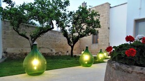 Outdoor decorative glass vases on a tiled patio with a stone wall and a tree in the background. - Li Perrini Boutique B&B (Vernole)