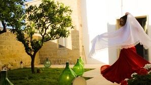 A courtyard with a tree, green glass bottles, and a red dress. - Li Perrini Boutique B&B (Vernole)
