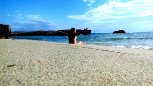 A beach scene with a person in the water and rocky formations in the background. - Li Perrini Boutique B&B (Vernole)