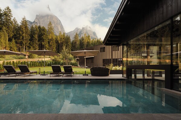 Una piscina cubierta, una piscina al aire libre, tumbonas
