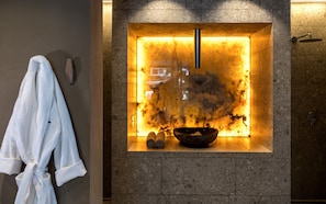 Relax in a serene bathroom with a unique stone wall feature and a bathtub.