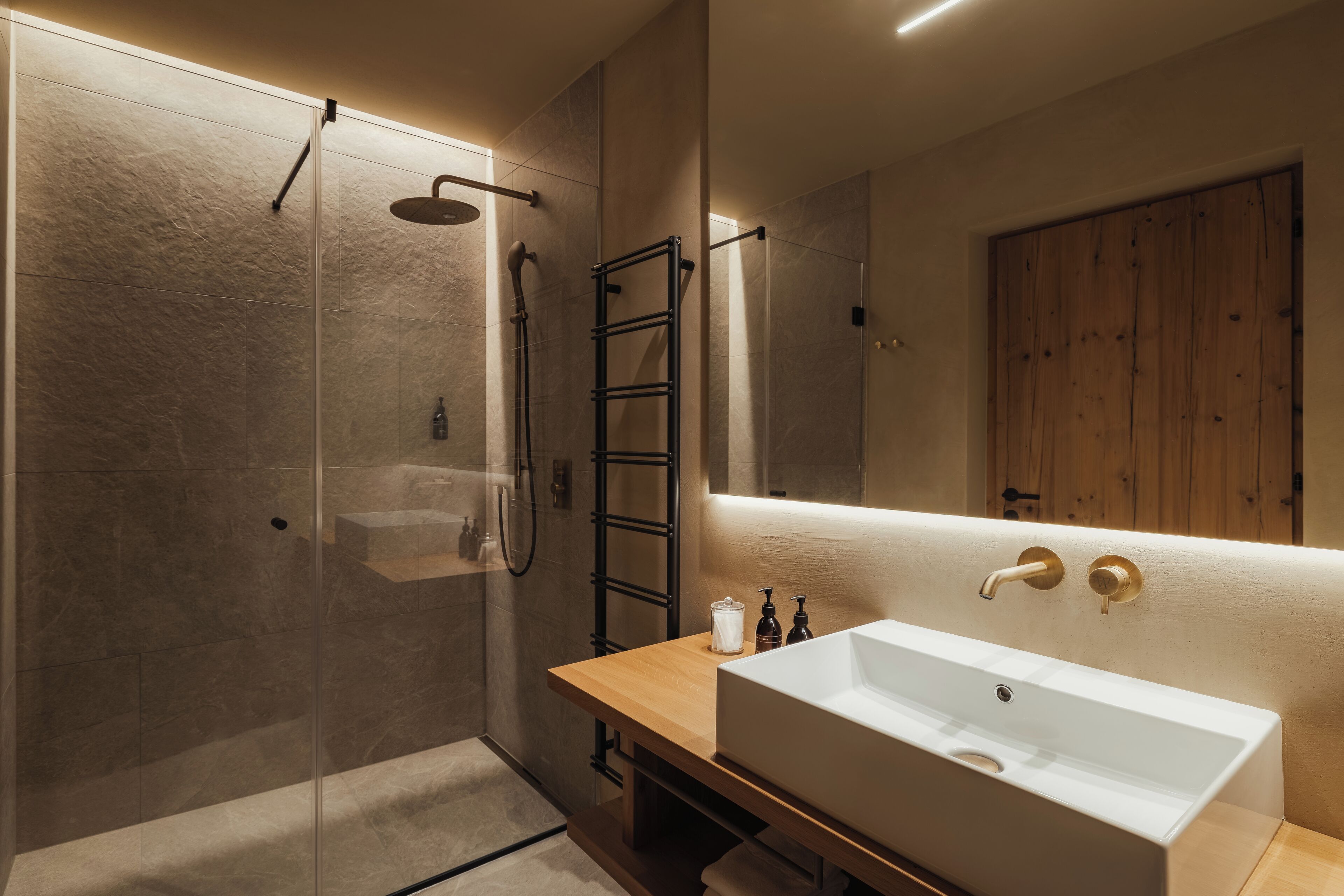 A modern bathroom with a glass-enclosed shower, a wooden vanity with a white sink, and a large mirror.
