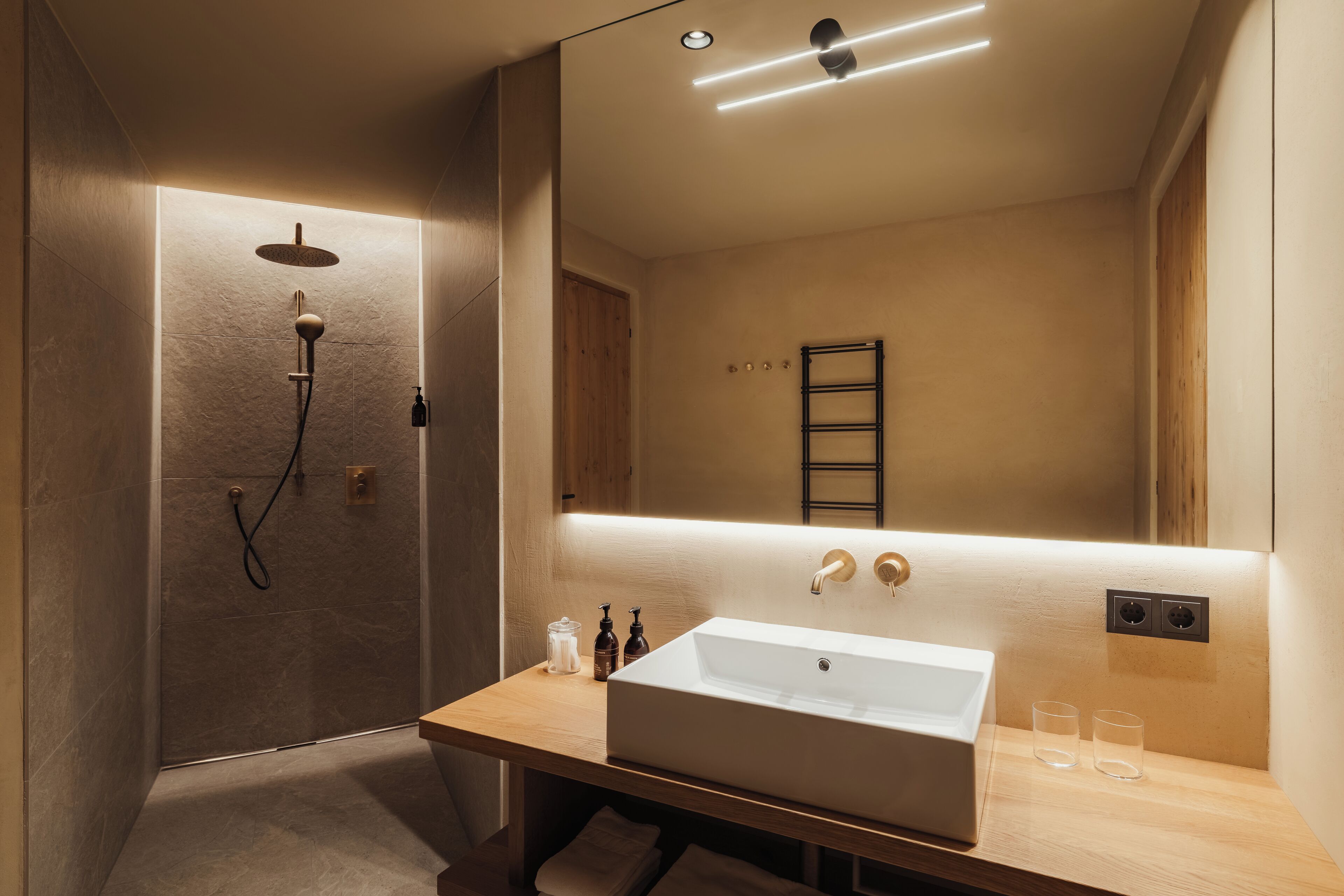 A modern bathroom with a large mirror, a sink, and a shower.