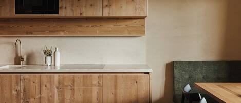 A kitchen with wooden cabinets, a microwave, a sink, and a green cushioned bench.