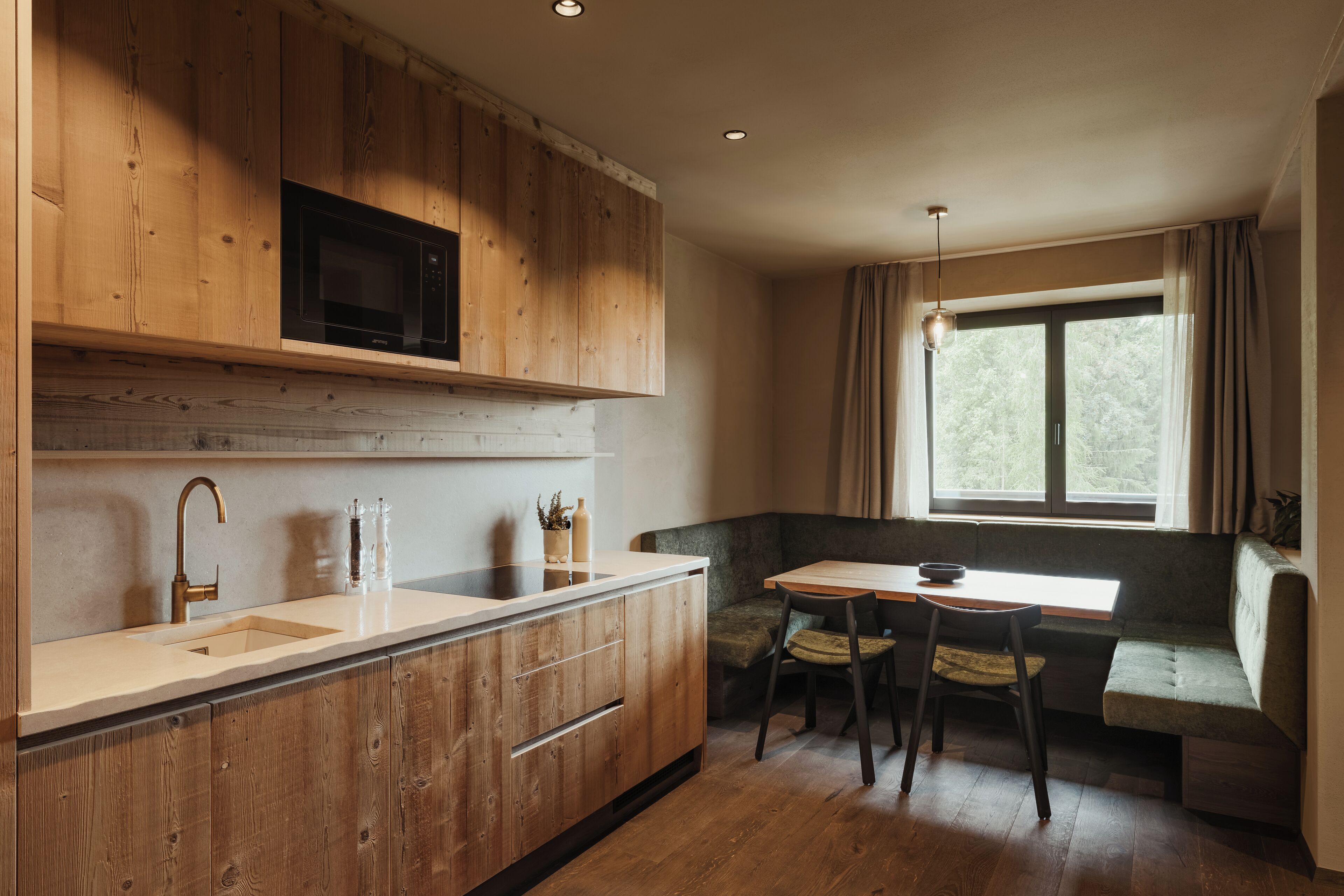 A kitchen with wooden cabinets, a built-in microwave, a sink, and a dining area with a table and chairs.