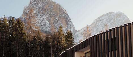 A modern building with a balcony, surrounded by snow-covered trees and mountains.
