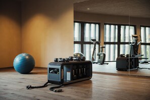 Un gimnasio con equipo de ejercicio, un espejo grande y una pelota azul para hacer ejercicio.