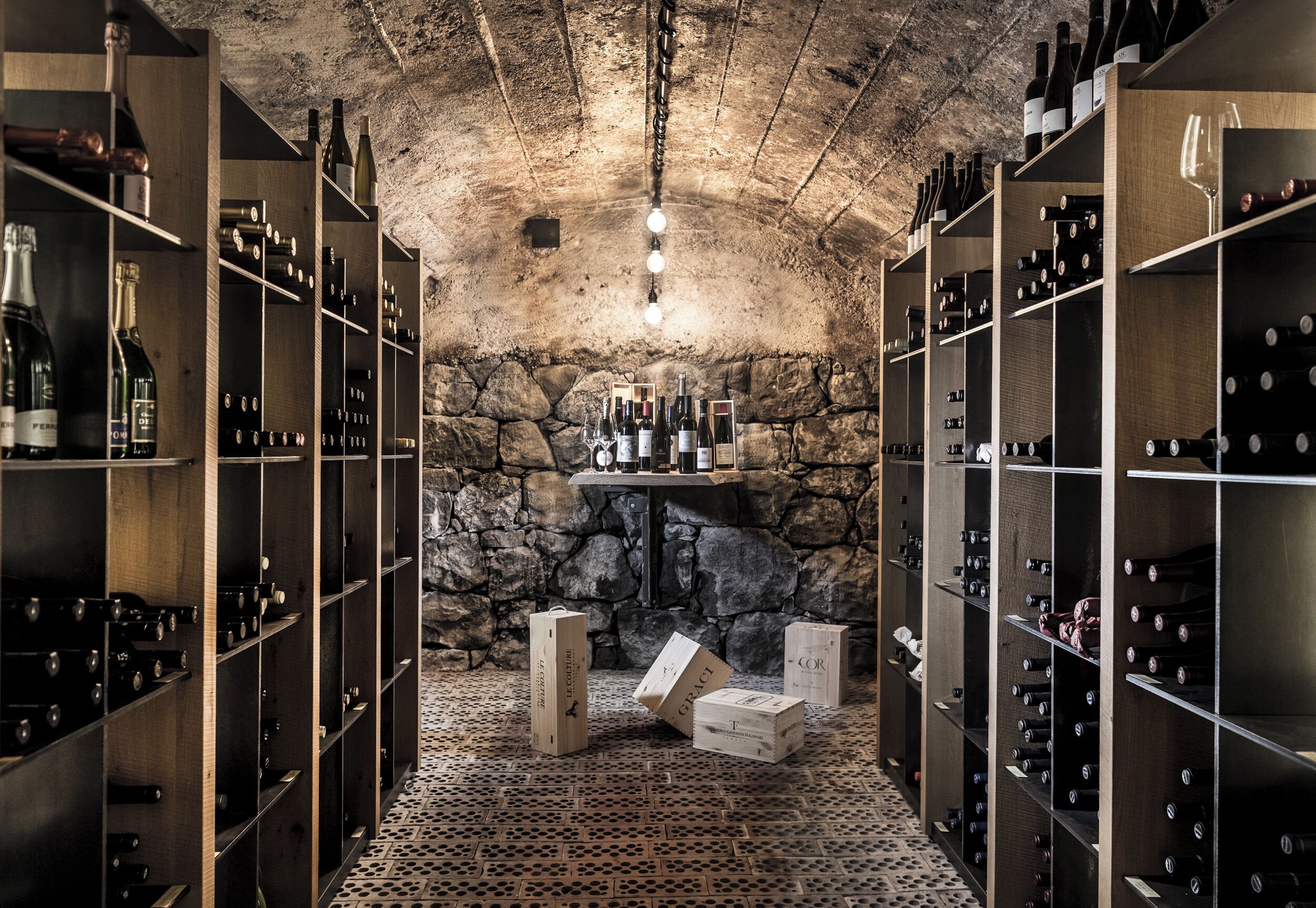 A wine cellar with wooden racks, stone walls, and a central display shelf.