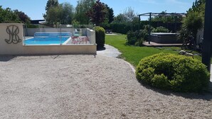 A swimming pool with a glass enclosure, surrounded by a gravel path and greenery. - Studios Marie Barrault (Les Herbiers)