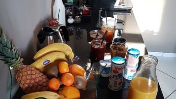 Una encimera de cocina con frutas, una cafetera y varios condimentos.