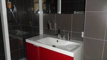 A bathroom with a white sink, red cabinet, and a mirror above the sink.