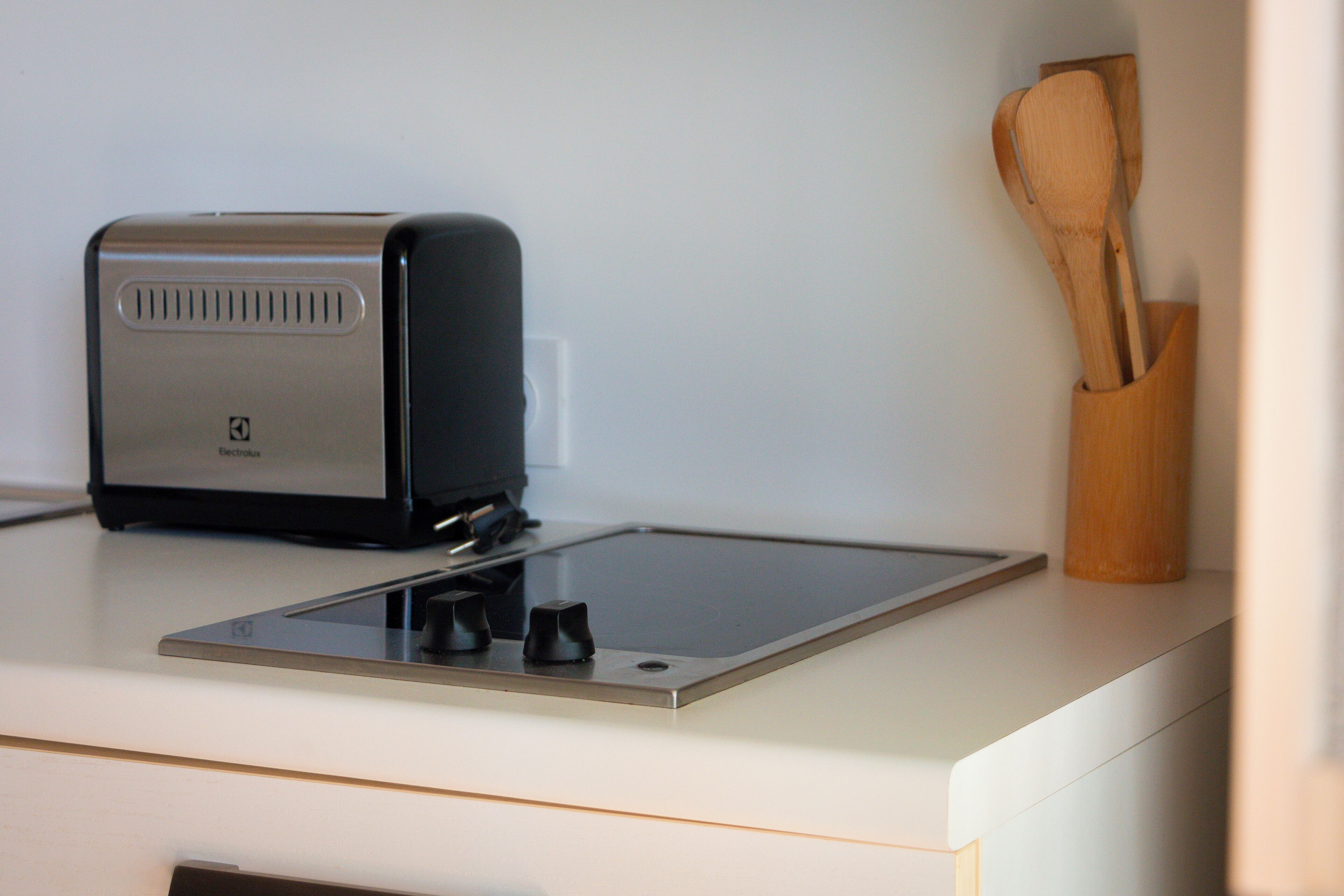 A kitchen with a toaster and a wooden utensil holder on the counter.