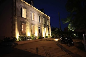 Un edificio histórico con ventanas iluminadas y un camino pavimentado.