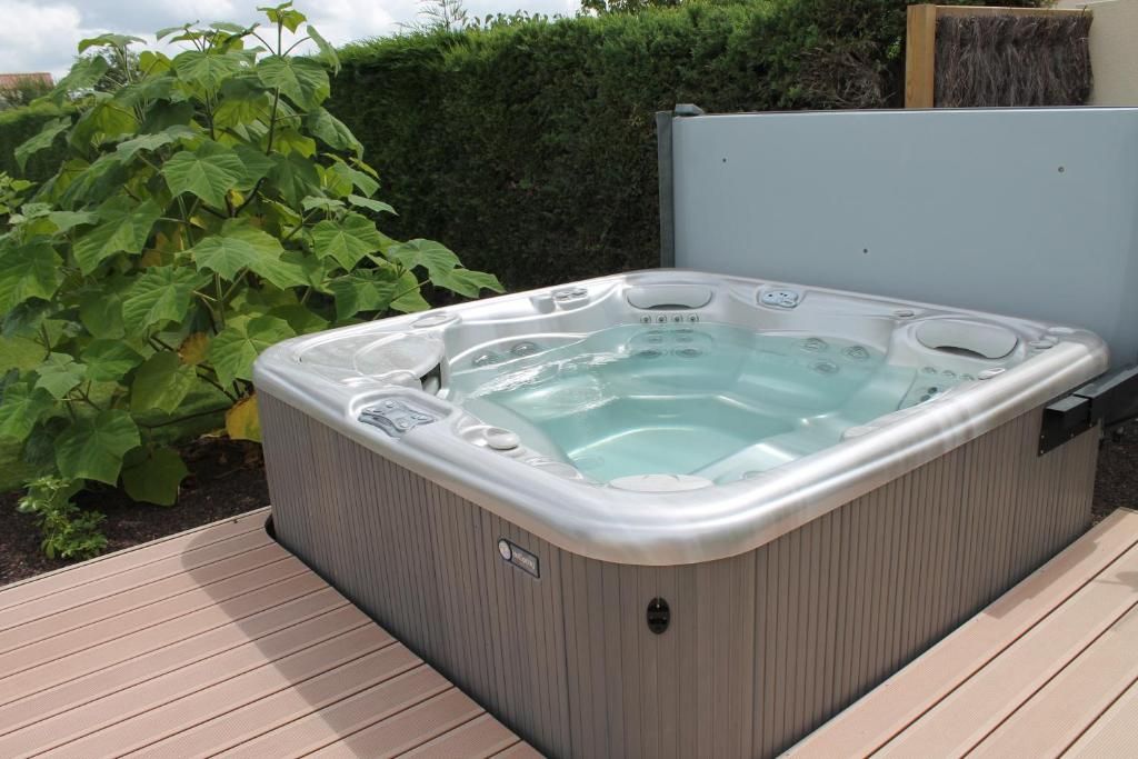 A hot tub with a control panel, surrounded by a wooden deck and greenery.