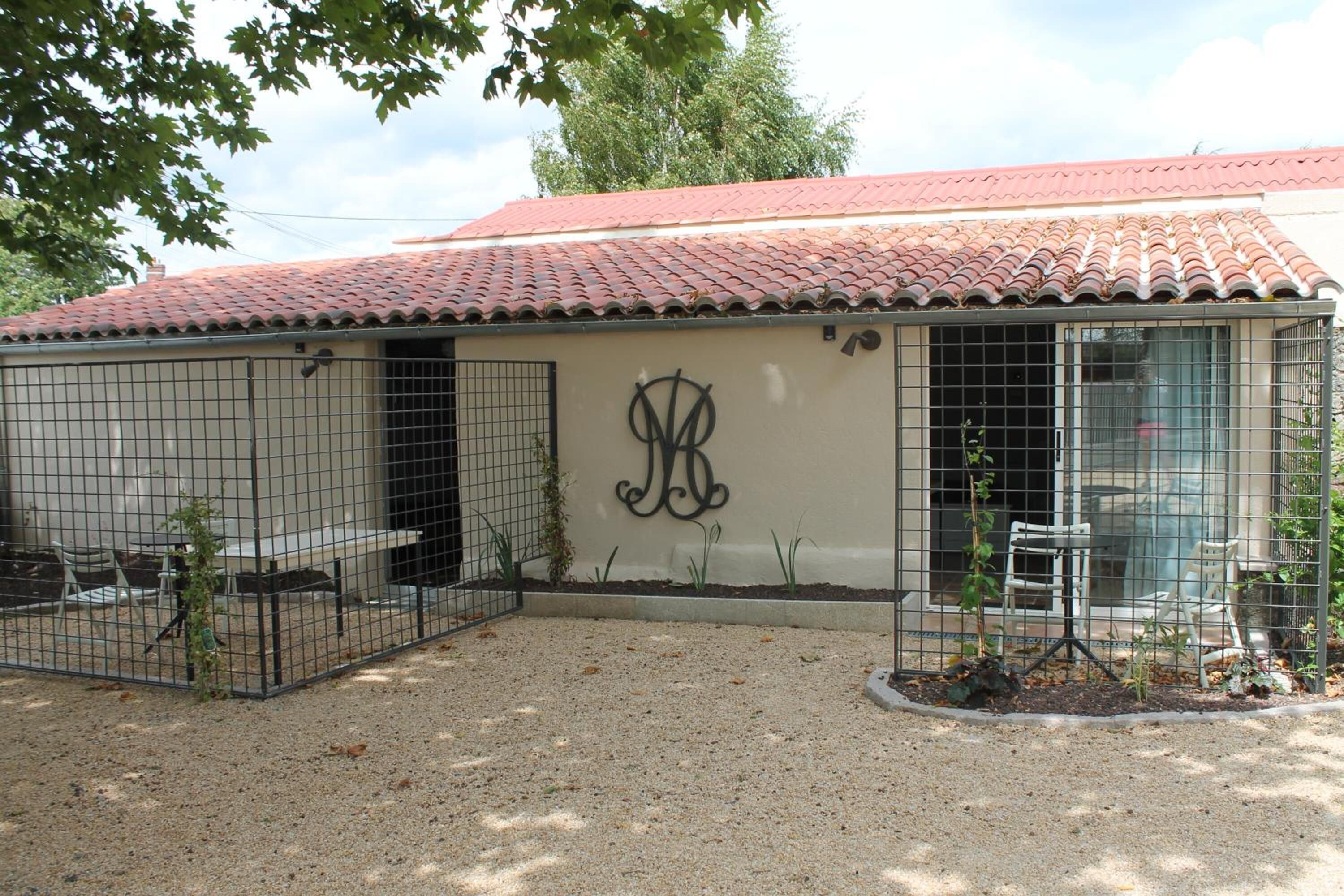 Un bâtiment avec un toit en tuiles, une clôture en métal et la lettre « A » peinte sur le mur.