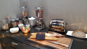 A kitchen counter with various food items, including a loaf of bread, a cutting board, and a toaster. - Studios Marie Barrault (Les Herbiers)